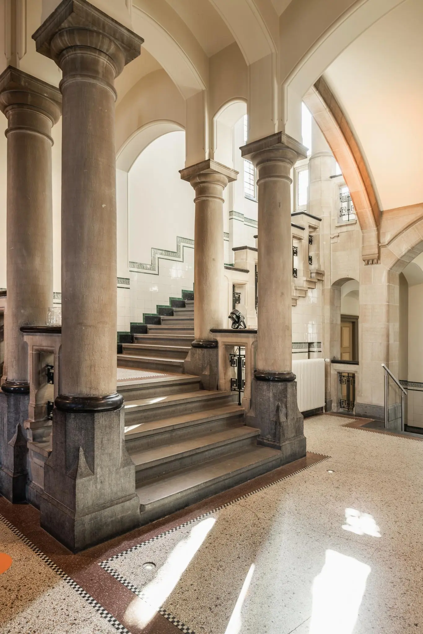 Monumentaal trappenhuis aan de Leidseweg met sierlijke zuilen, natuurstenen treden en betegelde wanden.