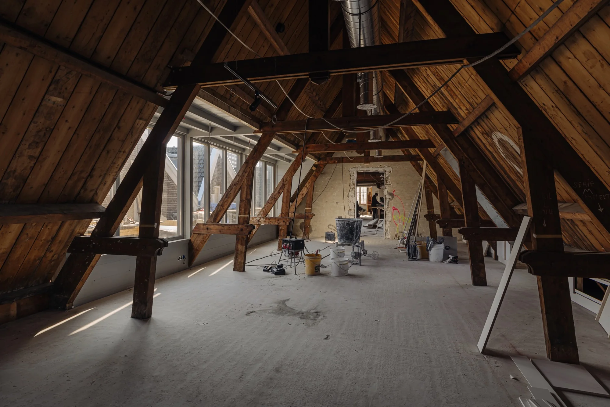 Zolderruimte aan de Leidseweg in verbouwing met zichtbaar houten spantwerk en bouwmaterialen.