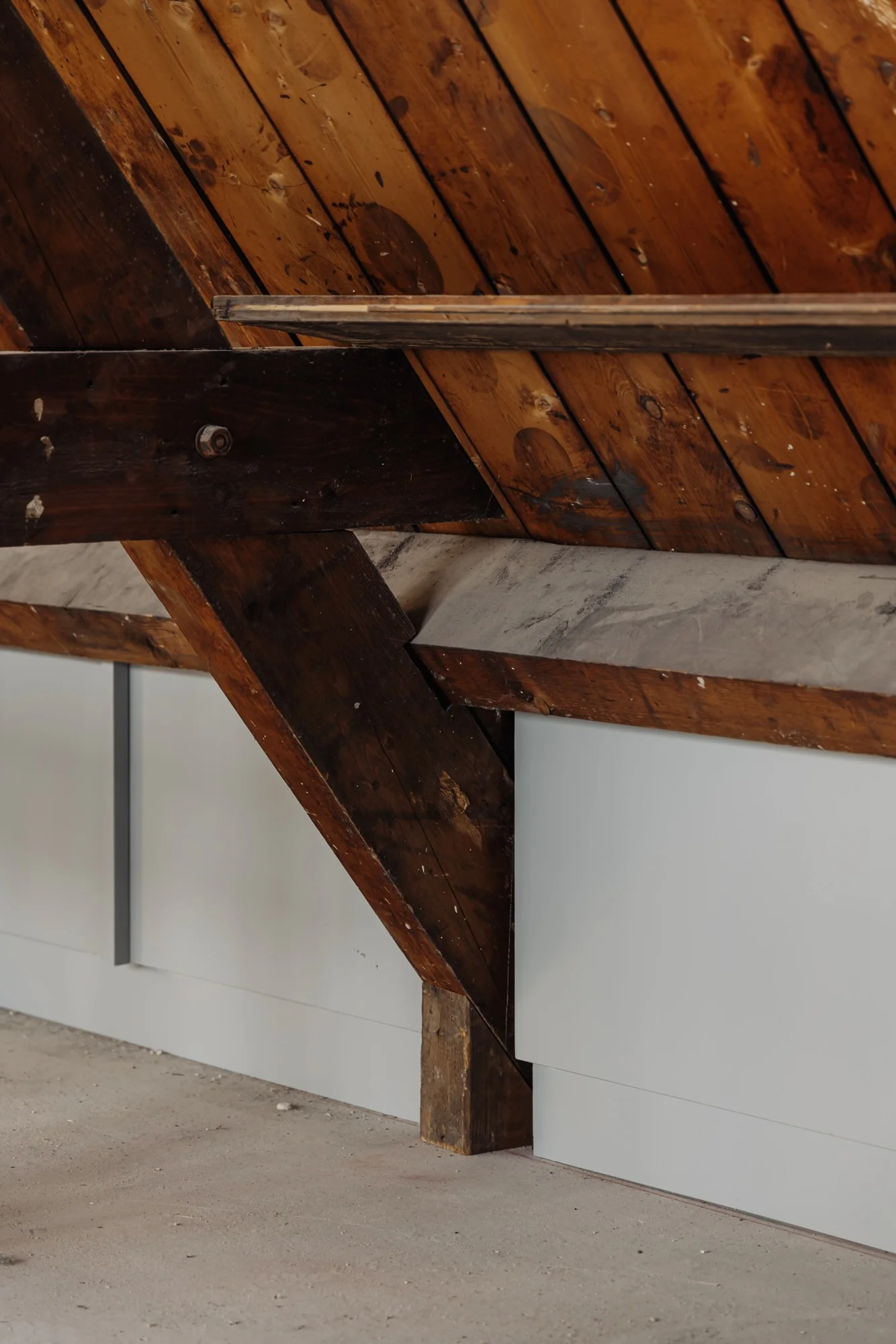 Houten dakconstructie met zichtbare balken en witte wandbekleding in een ruimte aan de Leidseweg.