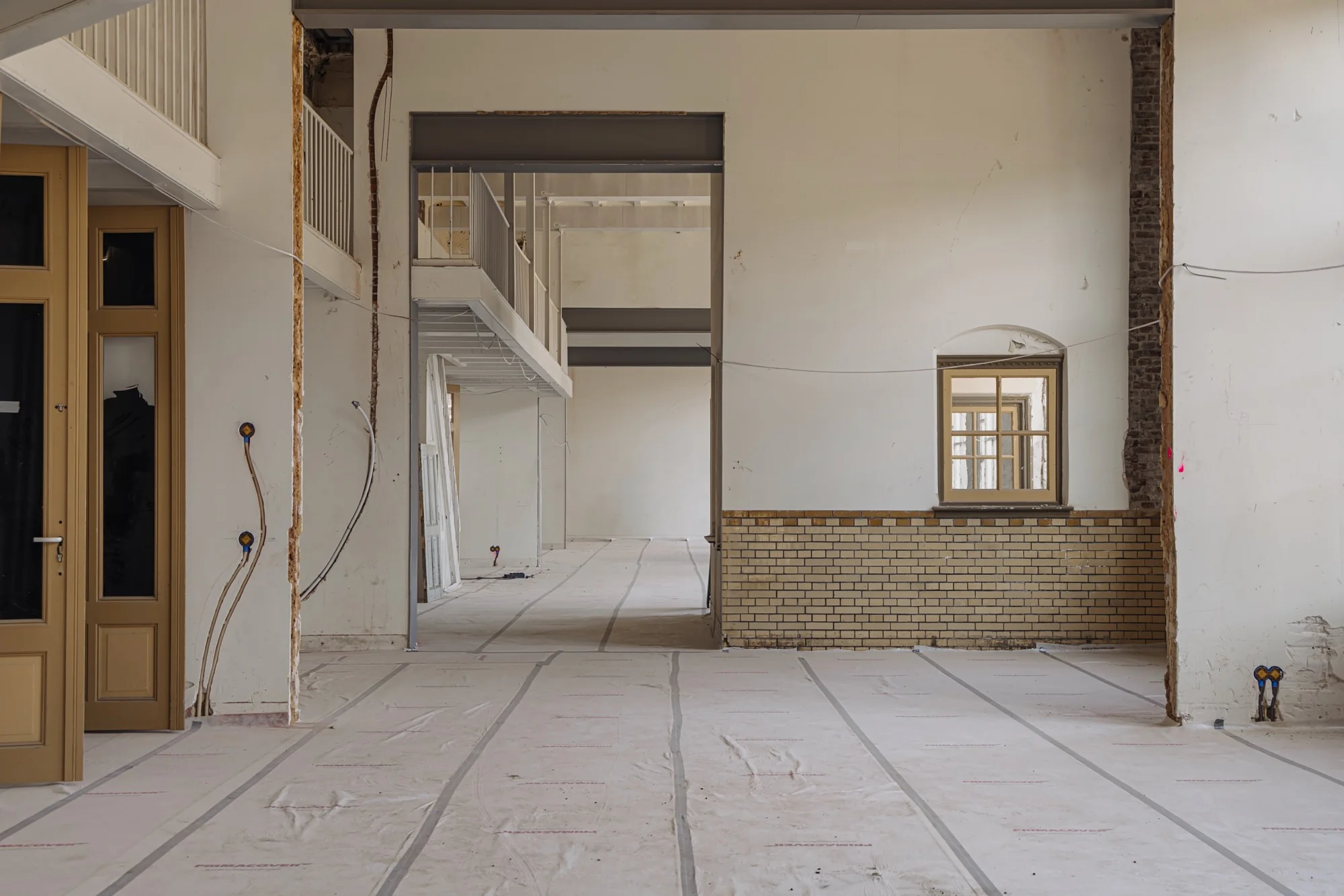Interieur van een pand aan de Leidseweg in verbouwing, met zicht op kale muren, afgedekte vloeren en een halve tussenverdieping.