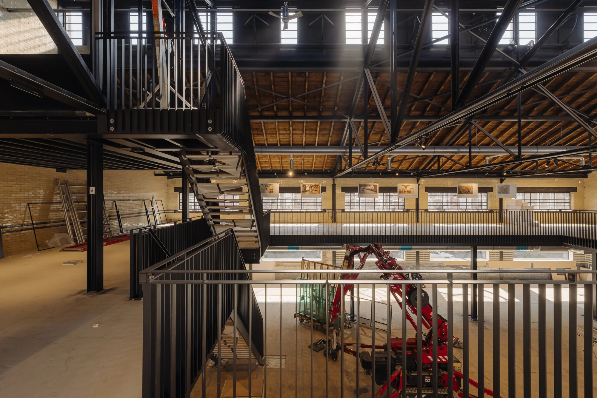 Industriële ruimte in renovatie aan de Muntkade met metalen trap, houten dakconstructie en bouwmaterieel op de begane grond.