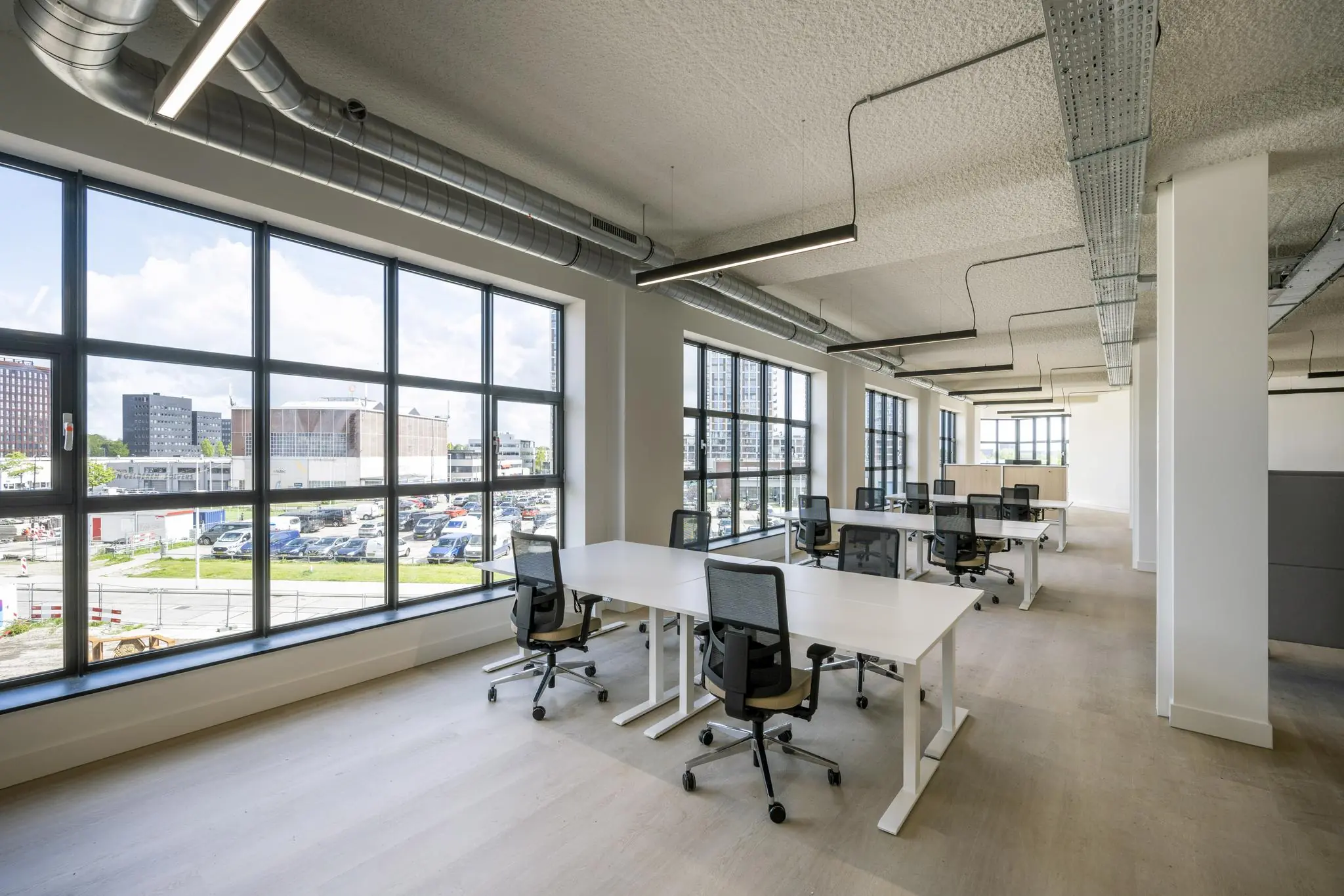 Modern en licht kantoor met grote ramen, witte bureaus en ergonomische bureaustoelen aan de Hellingbaan.