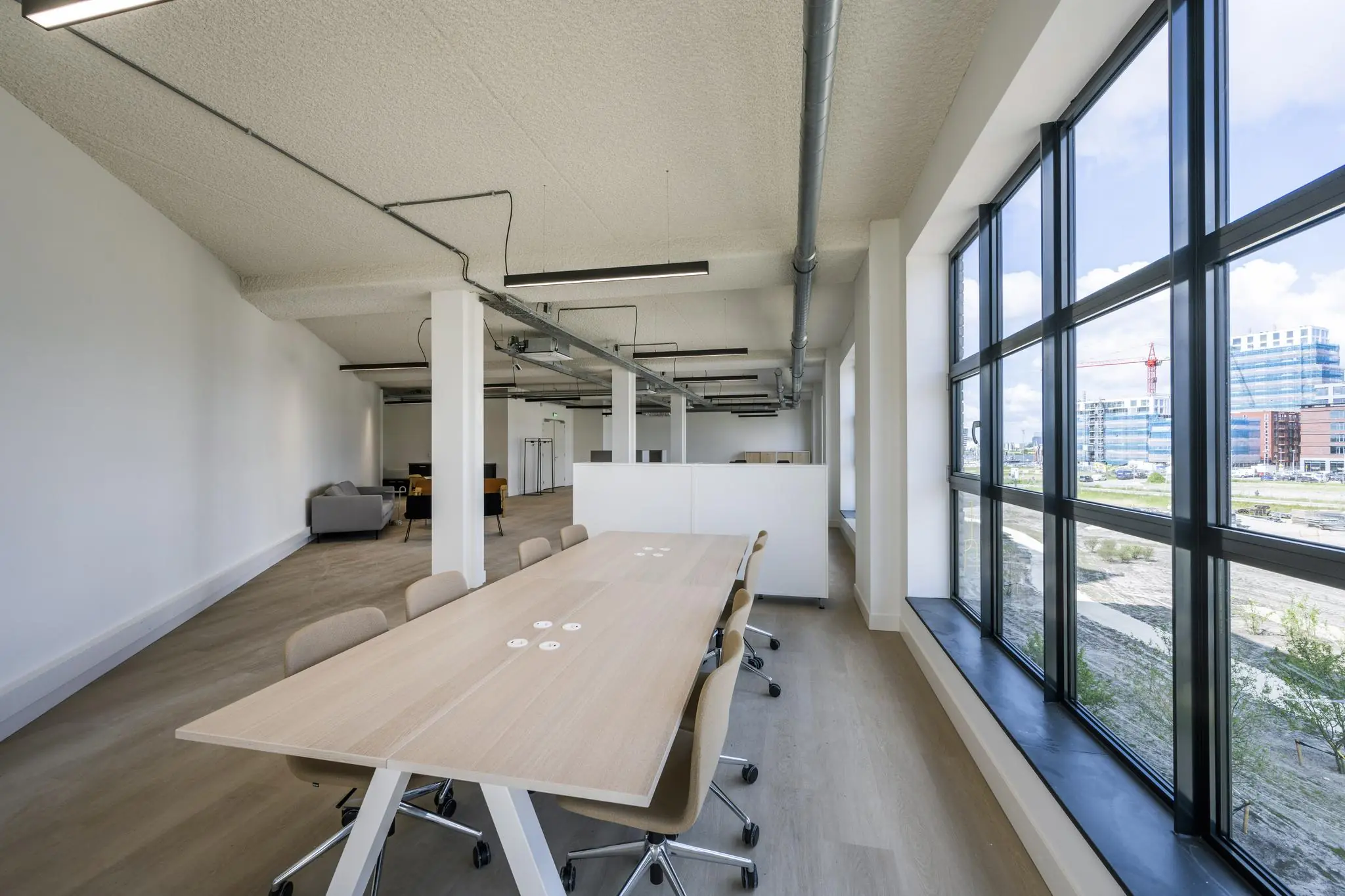 Moderne, open kantoorruimte met een vergadertafel en grote ramen met uitzicht op de Hellingbaan.