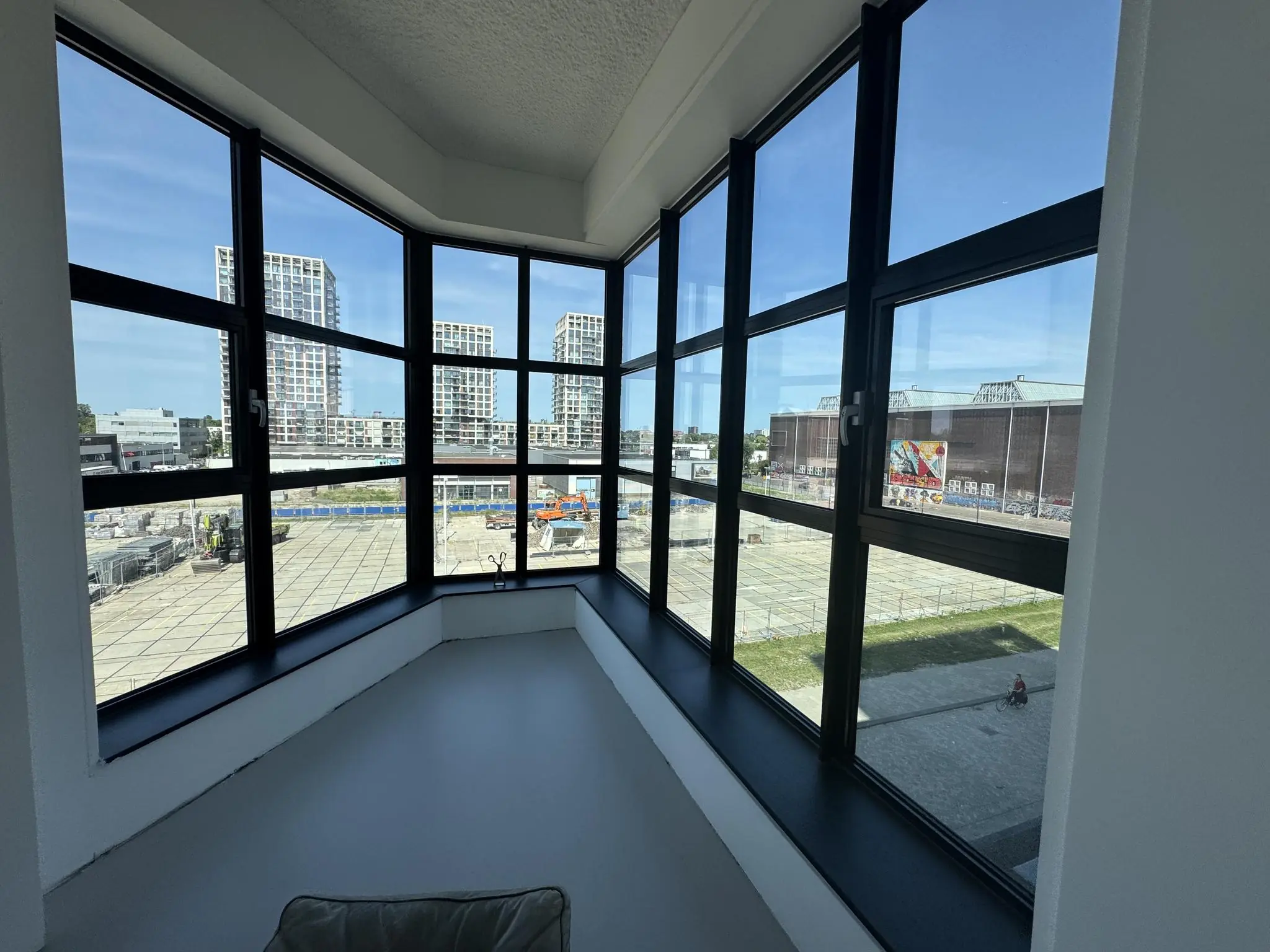 Uitzicht vanuit een hoekraam op een stedelijke bouwplaats en moderne woontorens bij de Hellingbaan.