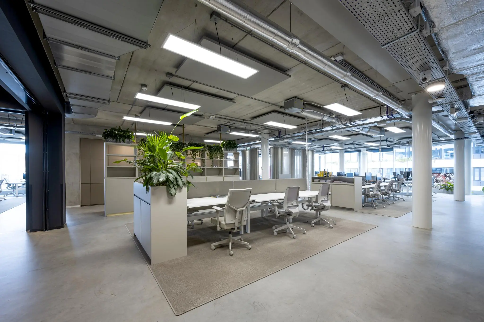 Moderne, open kantoorruimte aan de Moermanskkade met werkplekken, bureaustoelen en groene planten.