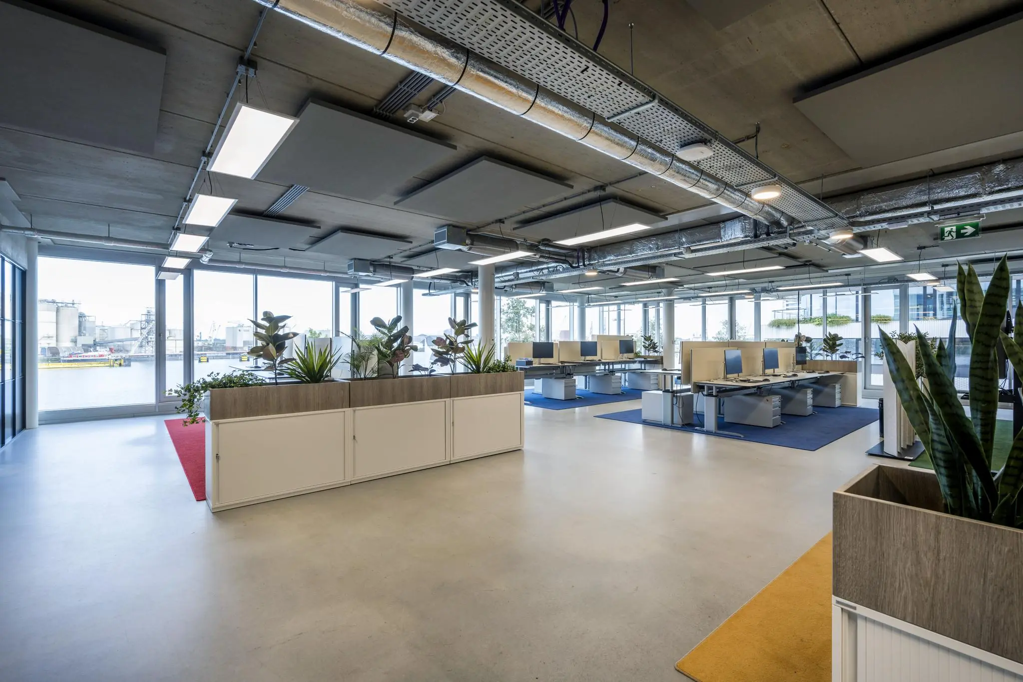 Moderne open kantoorruimte aan de Moermanskkade met werkplekken, planten en uitzicht op het water.