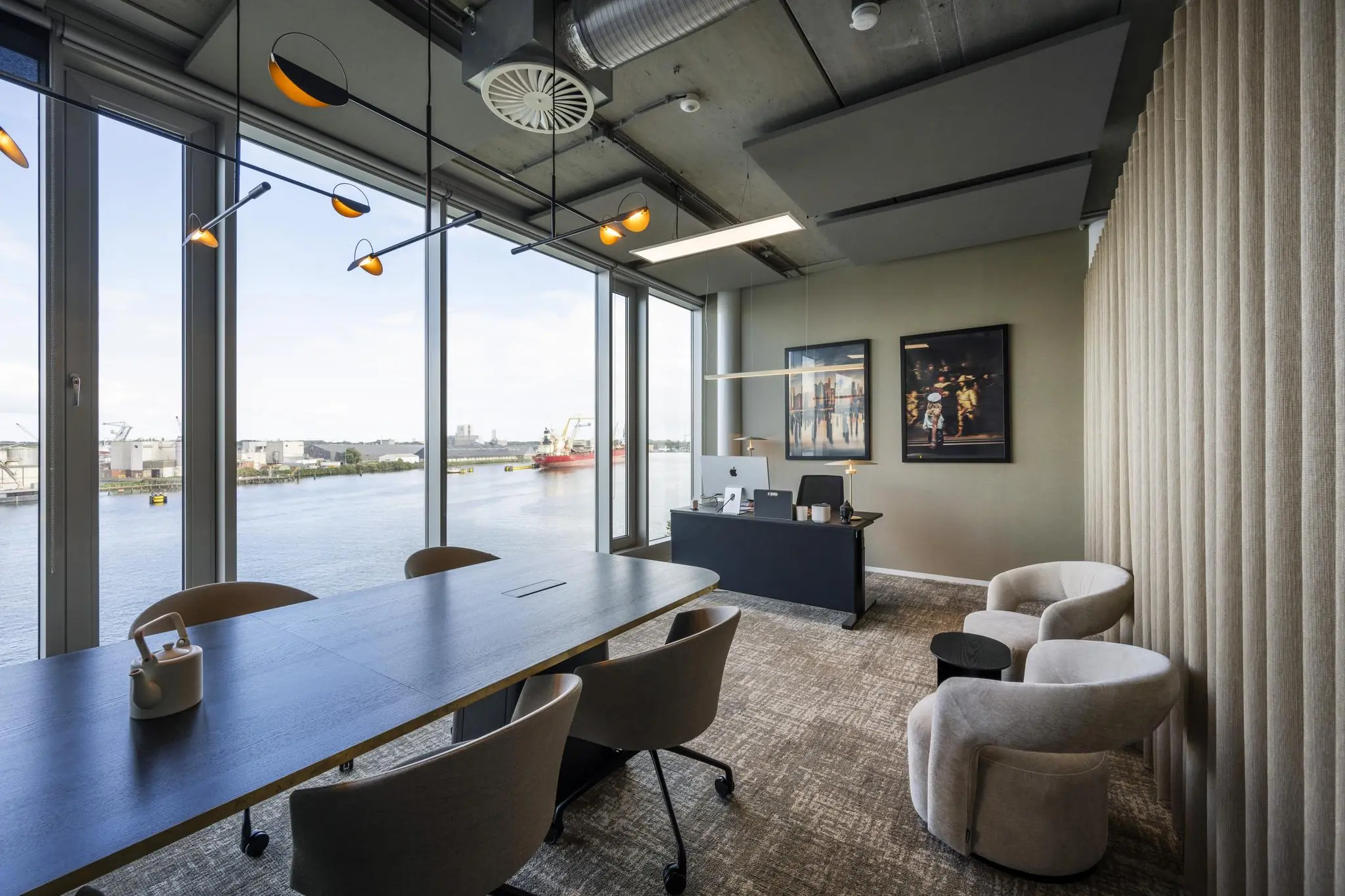 Modern kantoor met grote ramen aan het water aan de Moermanskade, ingericht met een vergadertafel, bureaumeubilair en kunst aan de muur.