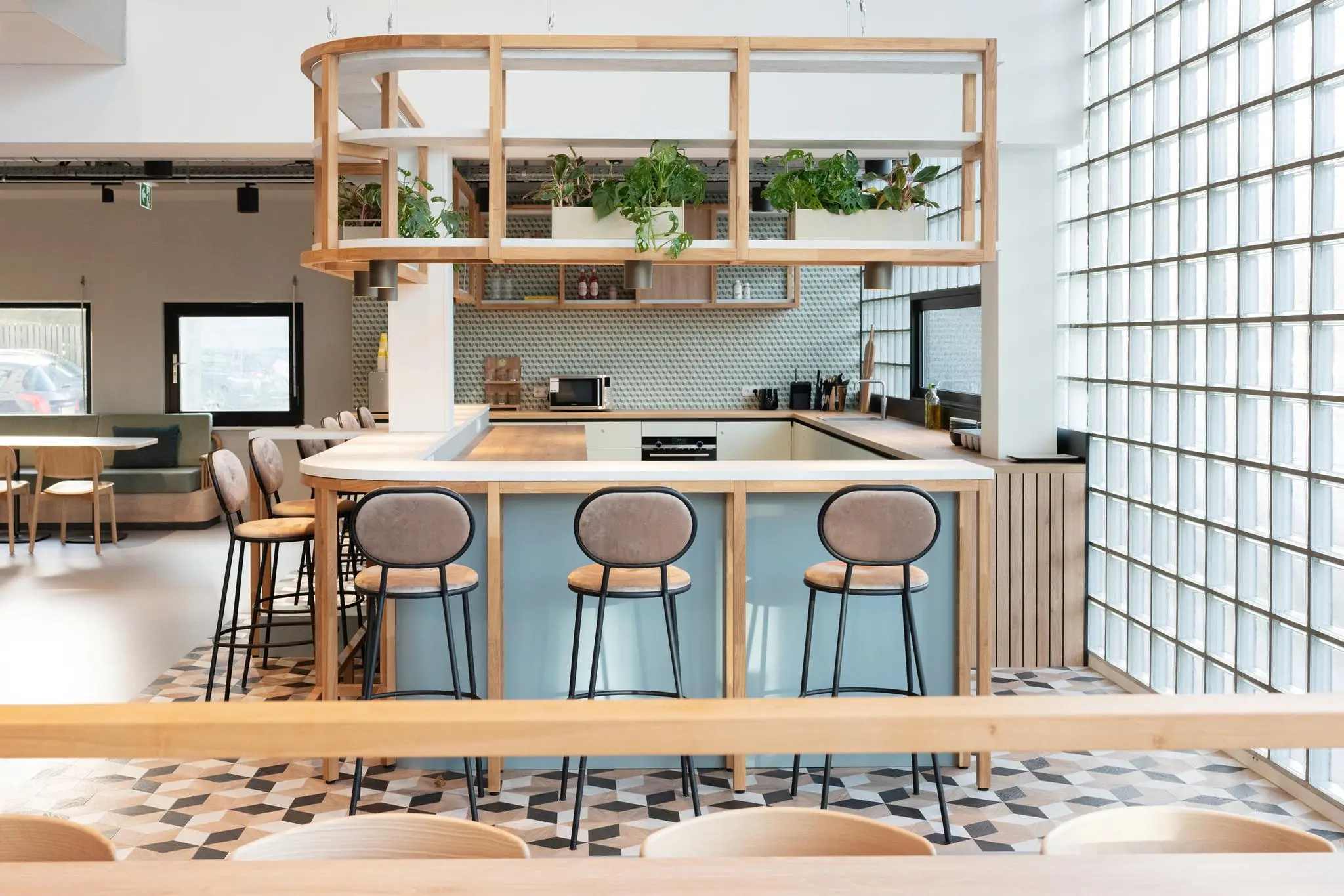 Moderne open keuken met bar, hoge krukken en hangende planten aan de Overschiestraat.