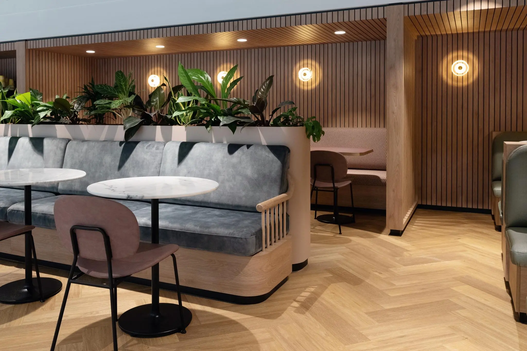 Modern ingerichte zithoek met houten lambrisering, planten en marmeren tafels in kantoorruimte aan de Overschiestraat.