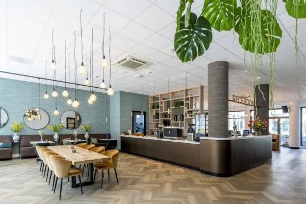 Moderne en stijlvol ingerichte ontvangsthal met houten vloer, zithoek, hanglampen en een receptiebalie aan het Elizabeth Cady Stantonplein.