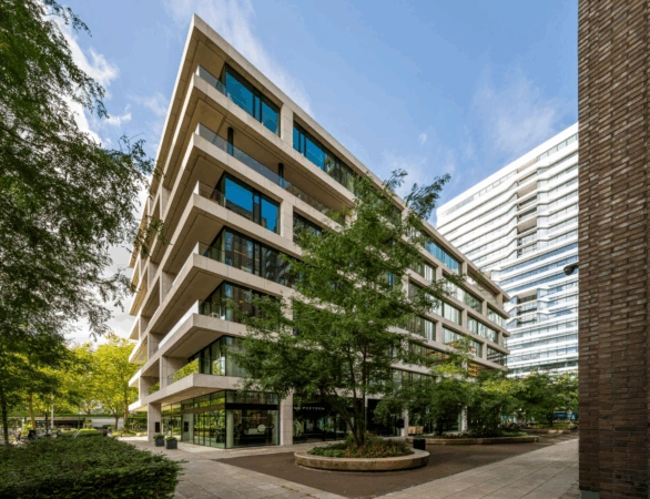 Modern kantoorgebouw aan de Gustav Mahlerlaan in Amsterdam met grote ramen en omringd door bomen.