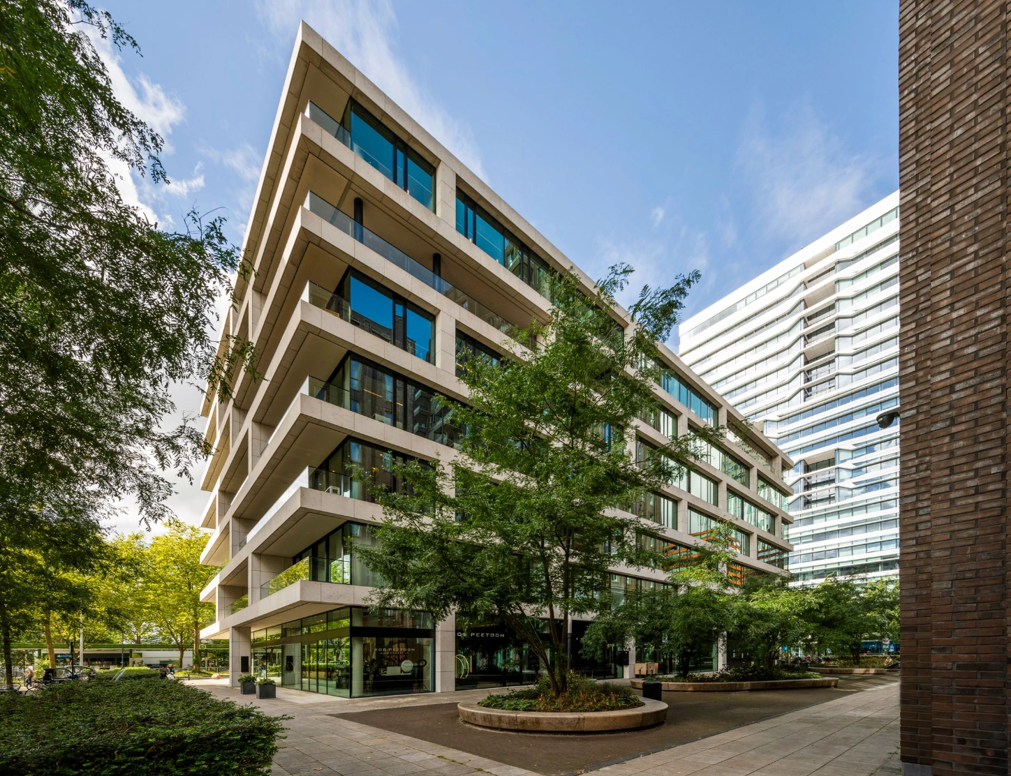 Modern kantoorgebouw aan de Gustav Mahlerlaan in Amsterdam met grote ramen en omringd door bomen.