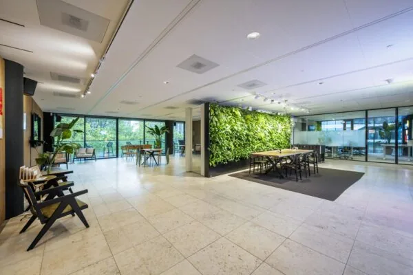 Moderne kantoorruimte aan de Gustav Mahlerlaan met grote ramen, een groene plantenwand en diverse zitgedeeltes.