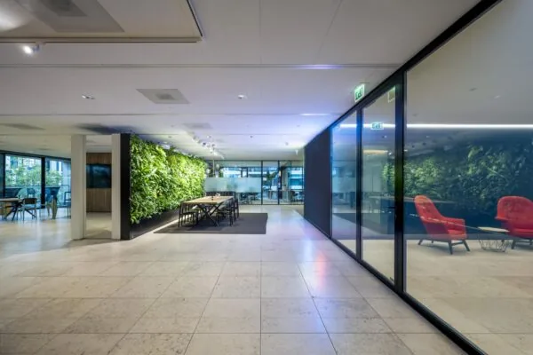 Moderne kantoorruimte aan de Gustav Mahlerlaan met een groene plantenwand, vergadertafel en glazen wanden.