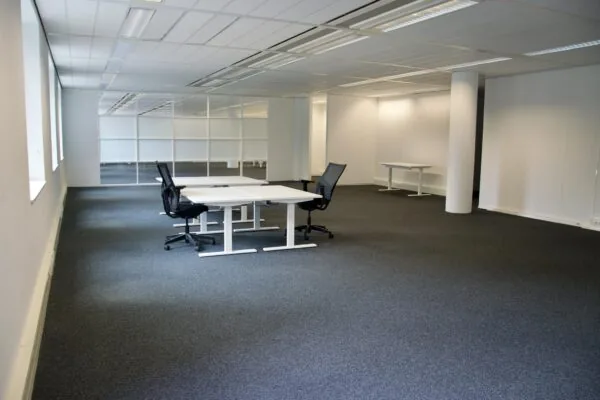 Moderne, open kantoorruimte met bureaus en bureaustoelen aan het Koningin Wilhelminaplein.