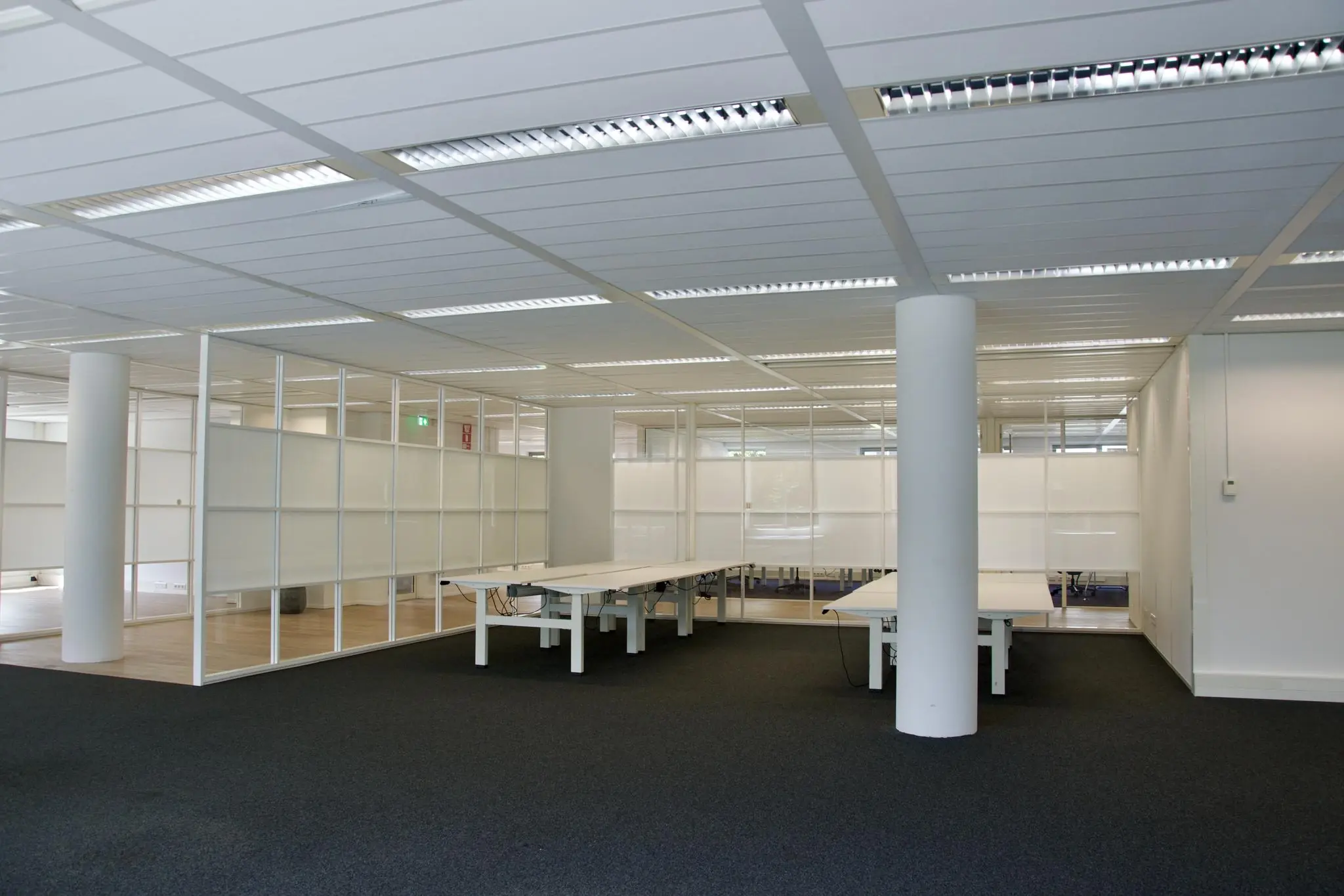 Moderne, open kantoorruimte met glazen wanden en werkplekken aan het Koningin Wilhelminaplein.