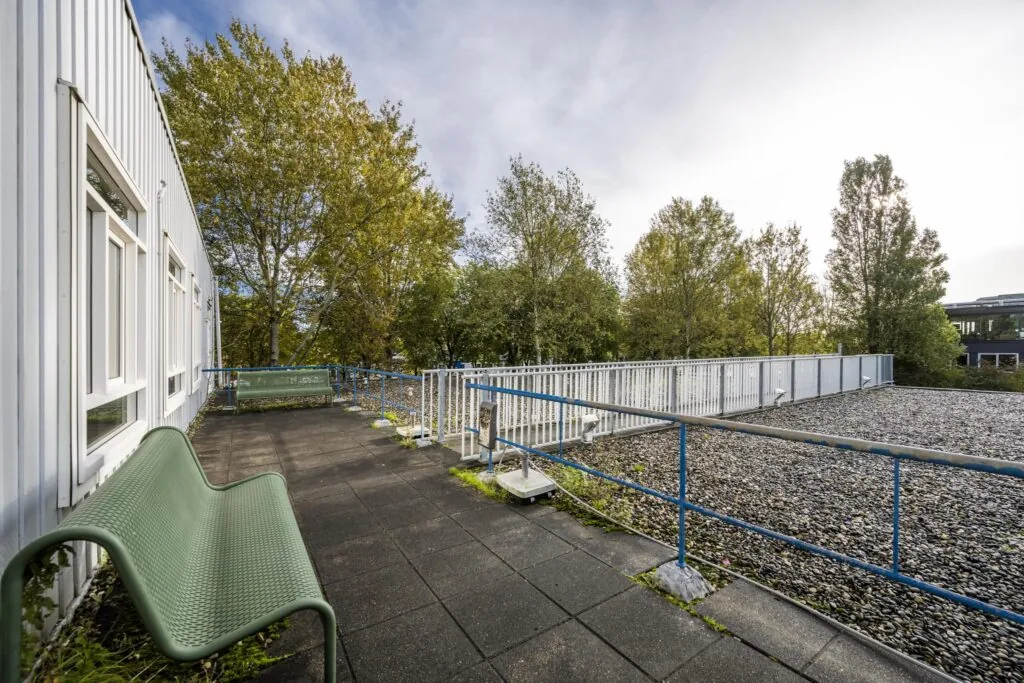 Dakterras met bankjes en uitzicht op bomen bij Van der Madeweg in Amsterdam.