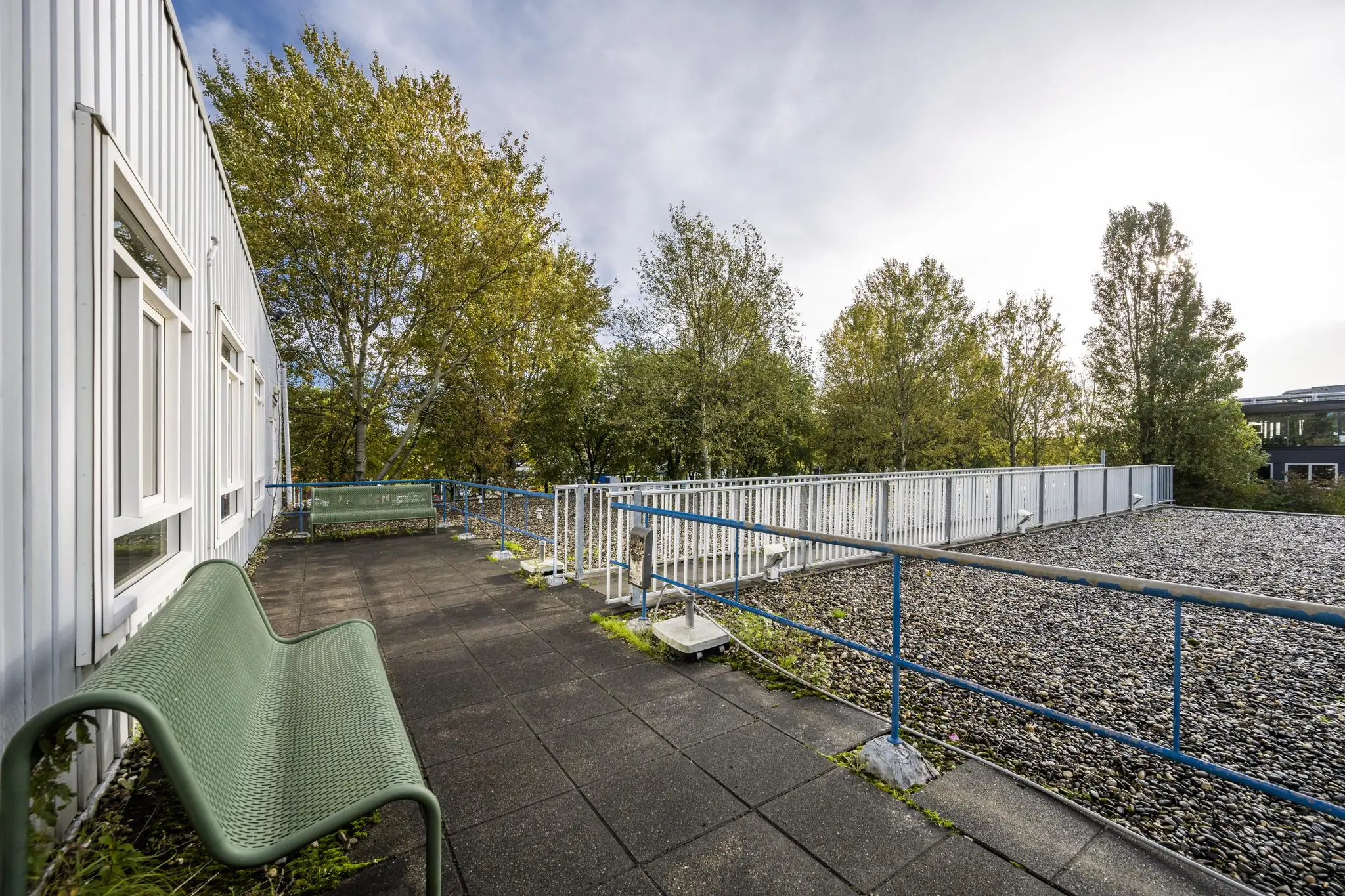 Dakterras met bankjes en uitzicht op bomen bij Van der Madeweg in Amsterdam.