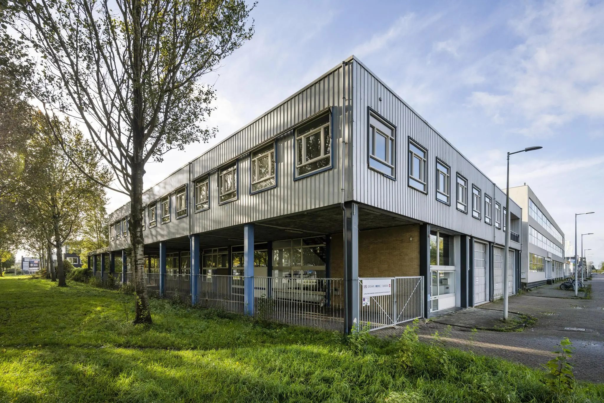Bedrijfsverzamelgebouw aan de Van der Madeweg met metalen gevelbekleding en parkeerplaatsen aan de voorkant.