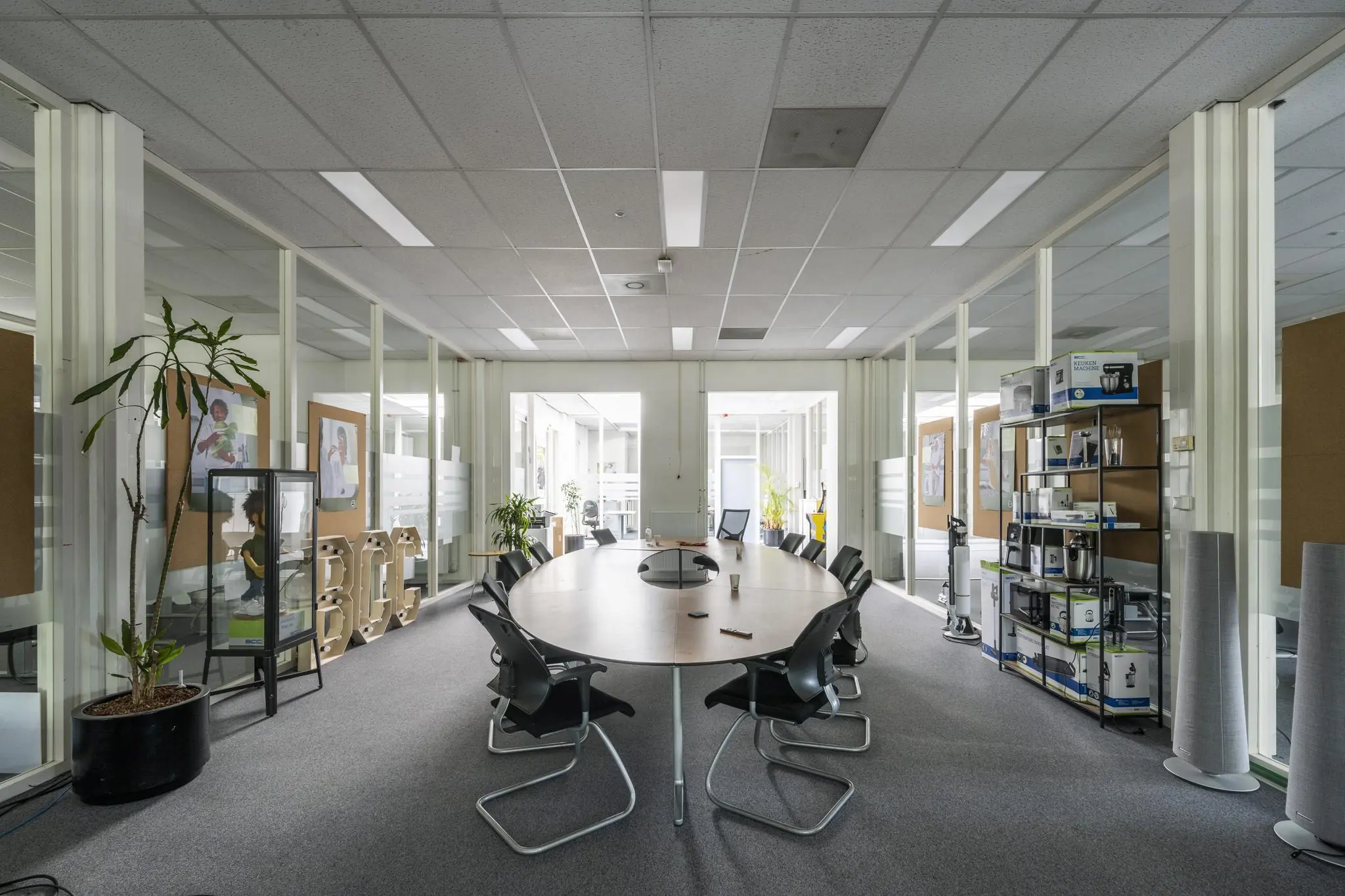 Vergaderruimte bij Van der Madeweg met ovale tafel, stoelen en kasten vol BCC-elektronica.