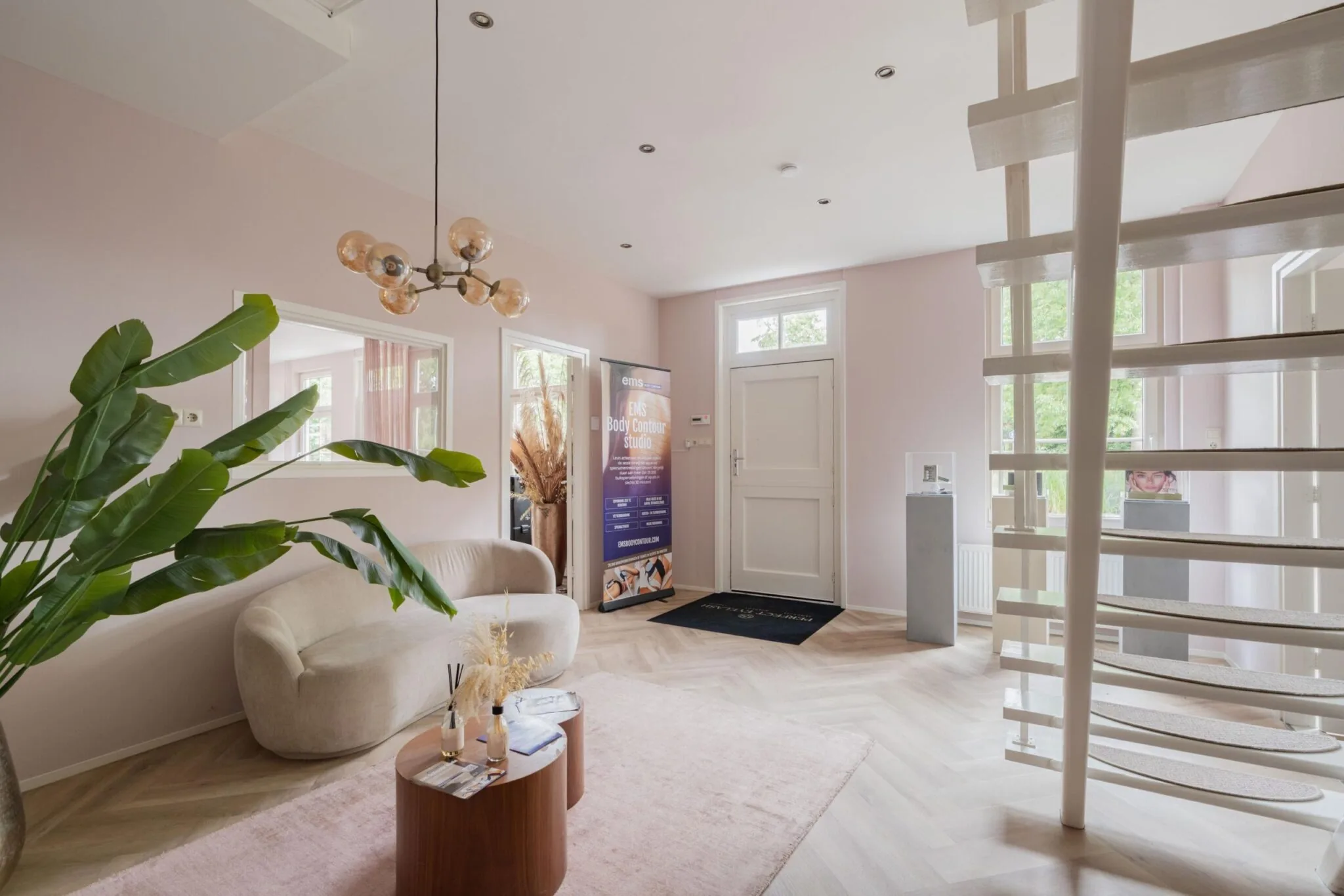 Stijlvolle en lichte wachtruimte van EMS Body Contour Studio aan de Sloterweg, met moderne inrichting en een witte draaitrap.