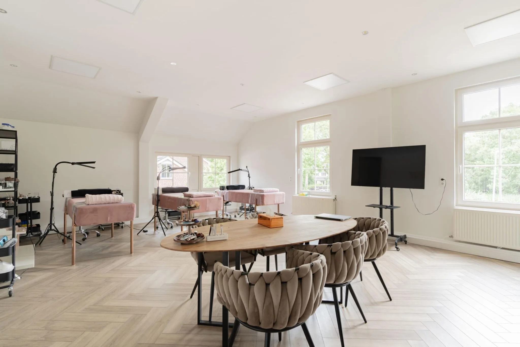 Lichte, moderne salonruimte aan de Sloterweg met behandelstoelen, vergadertafel en presentatiescherm.