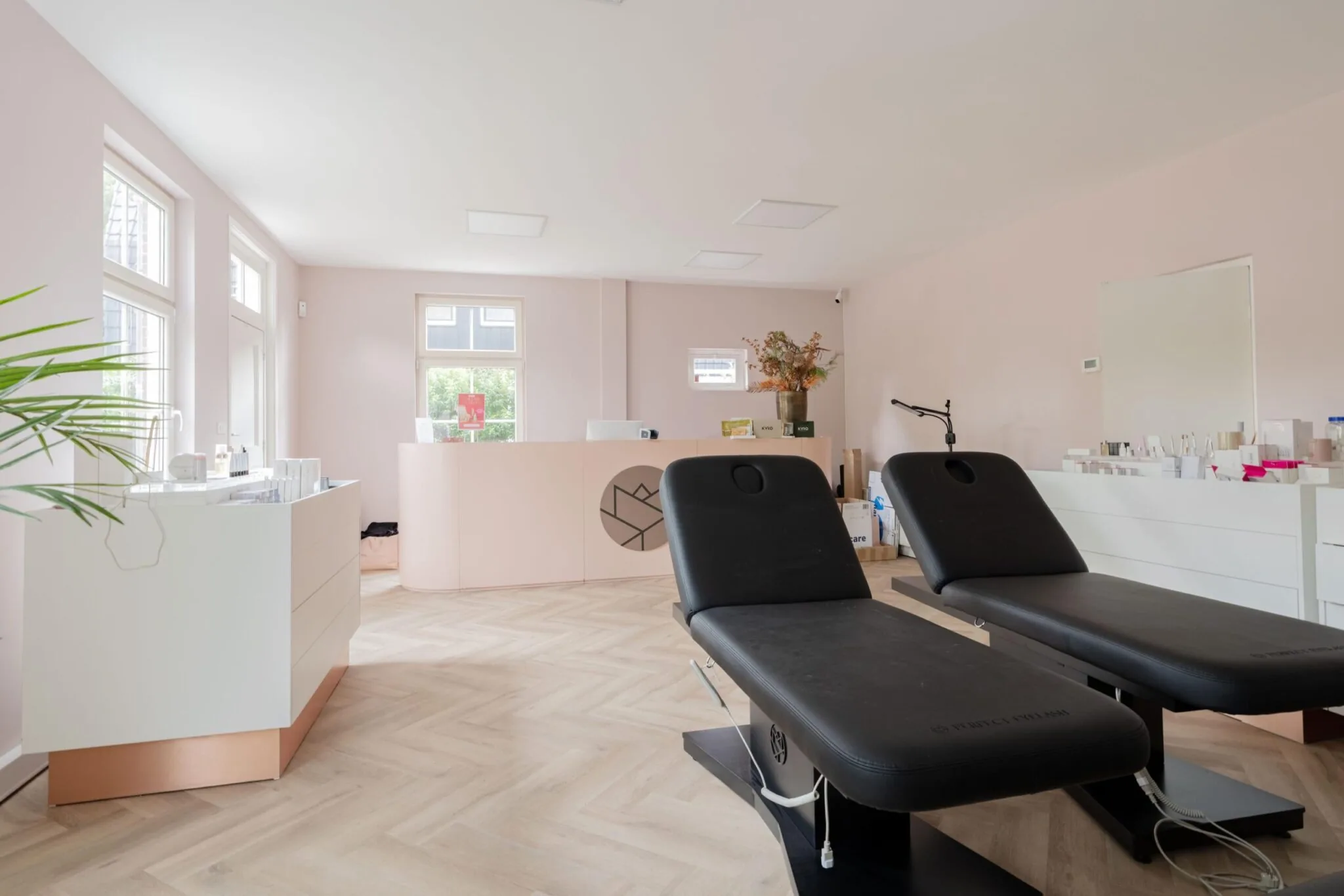 Moderne, licht ingerichte behandelkamer met twee zwarte behandelstoelen en een witte balie aan de Sloterweg.