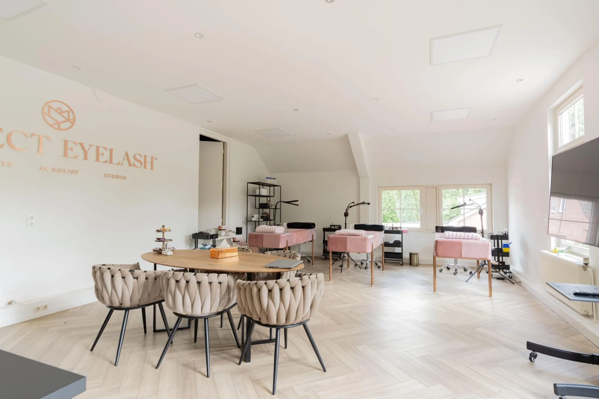 Lichte en moderne wimperstudio met behandelbedden en een ronde tafel met designstoelen aan de Sloterweg.