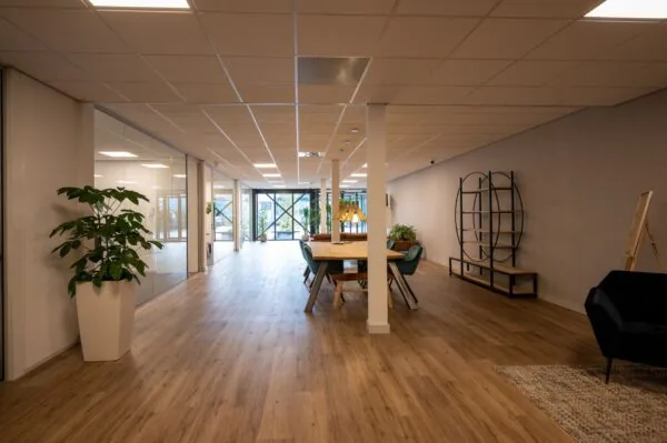 Moderne en ruimtelijke kantoorruimte aan de Vlierberg met houten vloer, glazen wanden en een gezellige zithoek.