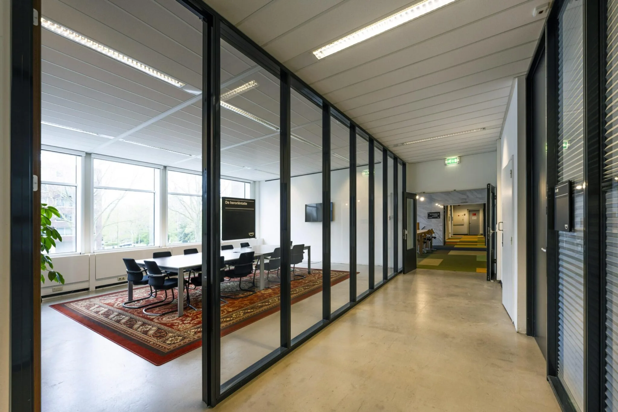 Moderne kantoorruimte aan de Laan van Kronenburg met glazen vergaderruimte en kleurrijk tapijt.