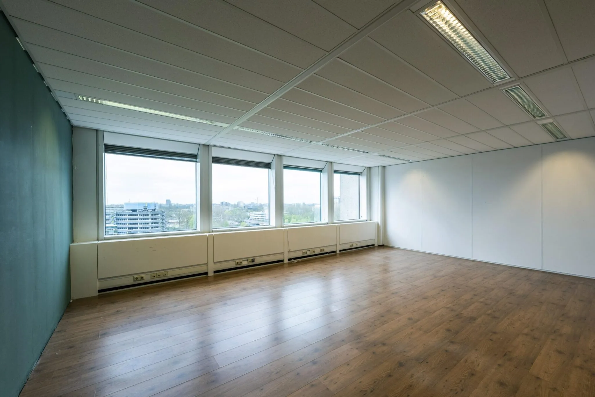 Lichte, lege kantoorruimte aan de Laan van Kronenburg met houten vloer en grote ramen met uitzicht op de stad.