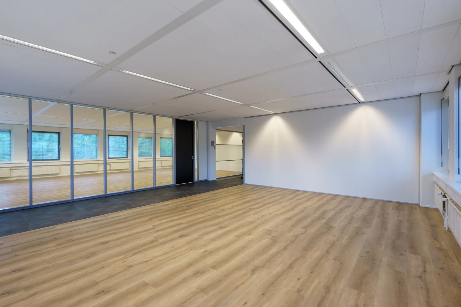 Leeg modern kantoor met houten vloer en glazen scheidingswand aan de Baarnsche Dijk.