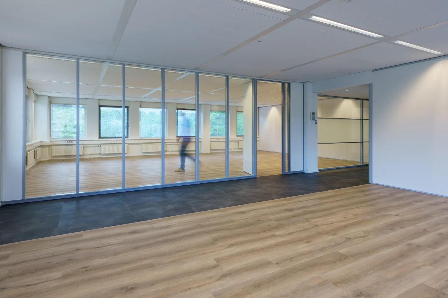 Moderne, lege kantoorruimte aan de Baarnsche Dijk met glazen wanden en houten vloer.