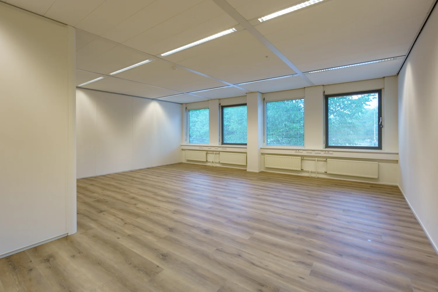 Leeg kantoorruimte met houten vloer en drie ramen aan de Baarnsche Dijk.