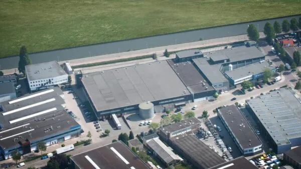 Luchtfoto van een bedrijventerrein aan de Weesperstraat met diverse bedrijfspanden en een naastgelegen kanaal.