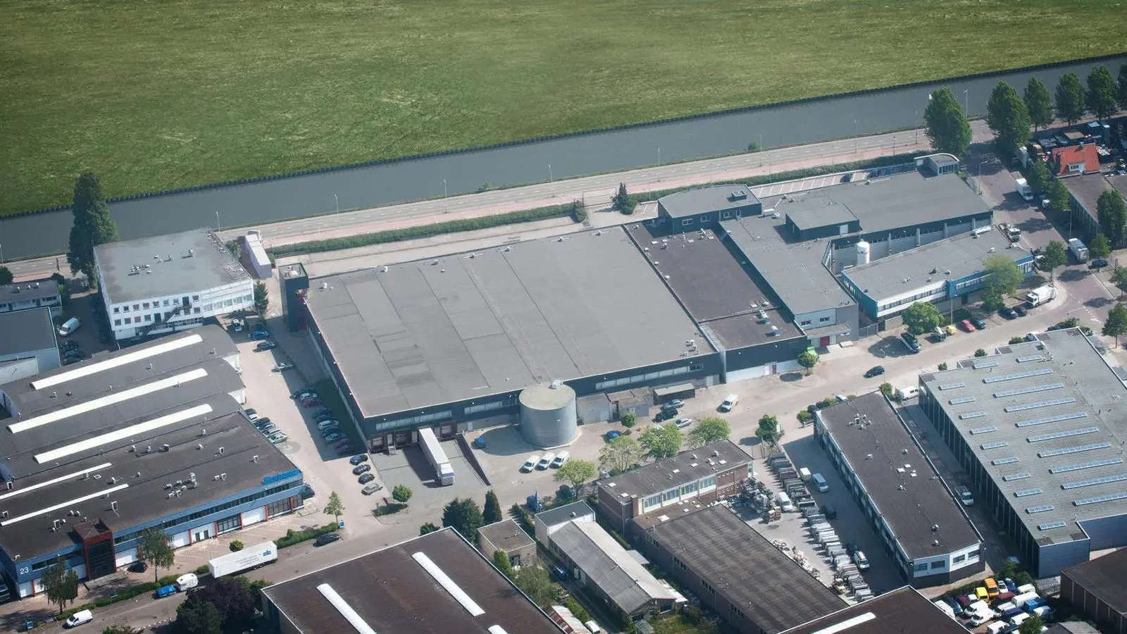 Luchtfoto van een bedrijventerrein aan de Weesperstraat met diverse bedrijfspanden en een naastgelegen kanaal.