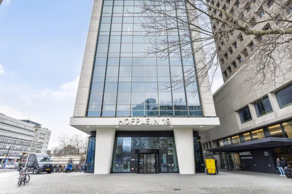 Vooraanzicht van het gebouw aan Hofplein 19 met fietsrekken en een DHL-bezorgwagen op de stoep.
