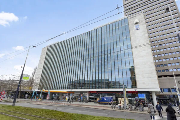 Een modern kantoorpand aan het Hofplein in Rotterdam, met een glazen façade en winkels op de begane grond.