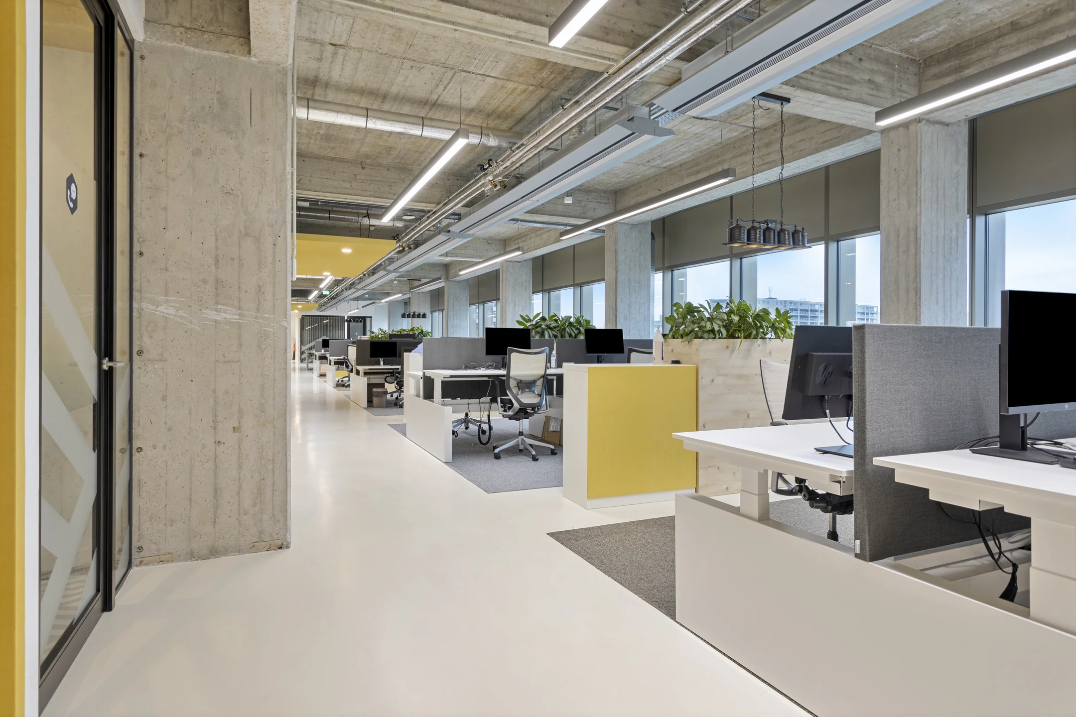 Een modern en ruim kantoorinterieur met open werkplekken en veel daglicht.