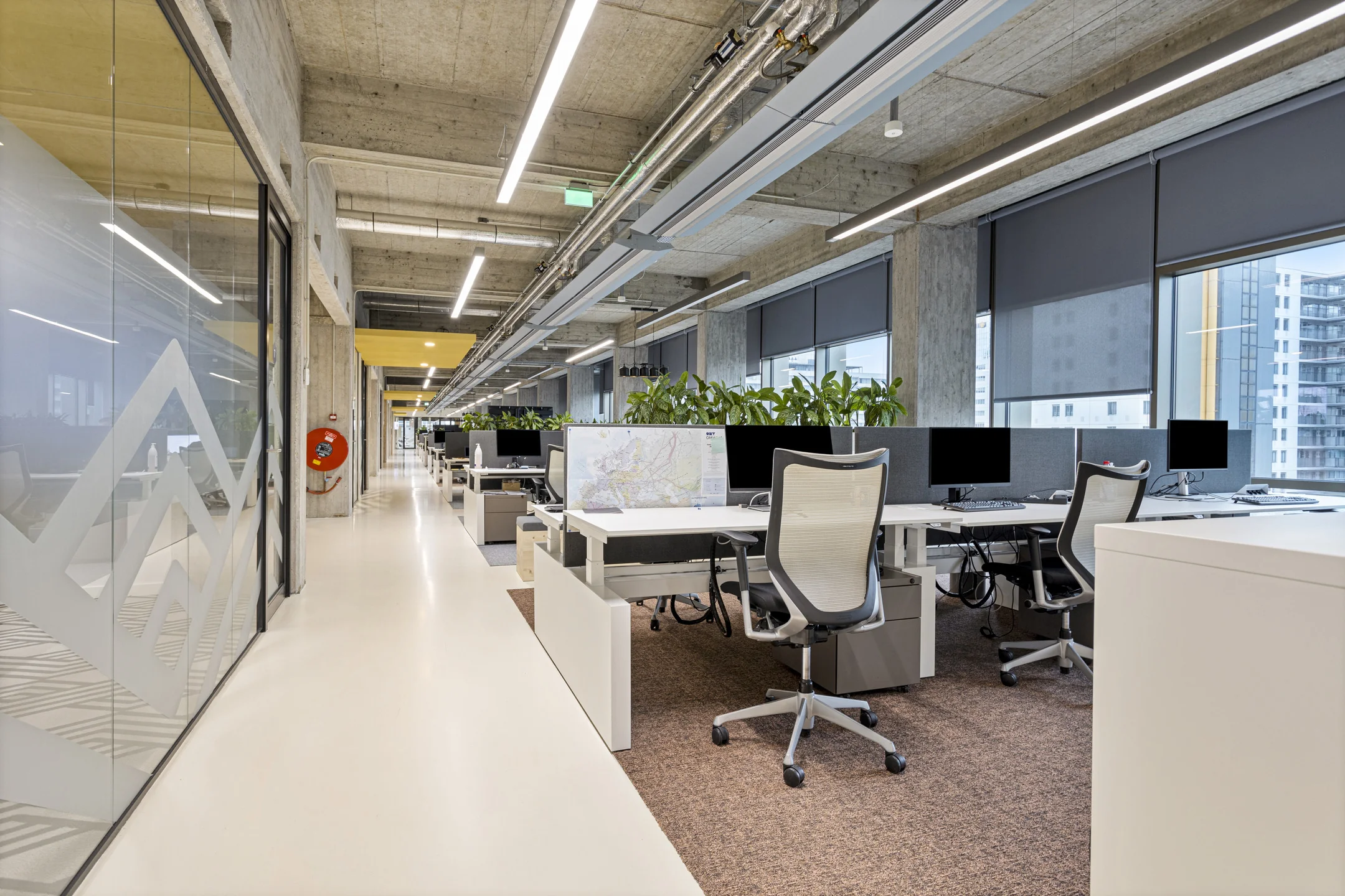 Een moderne, open kantoorruimte met flexwerkplekken en veel lichtinval.