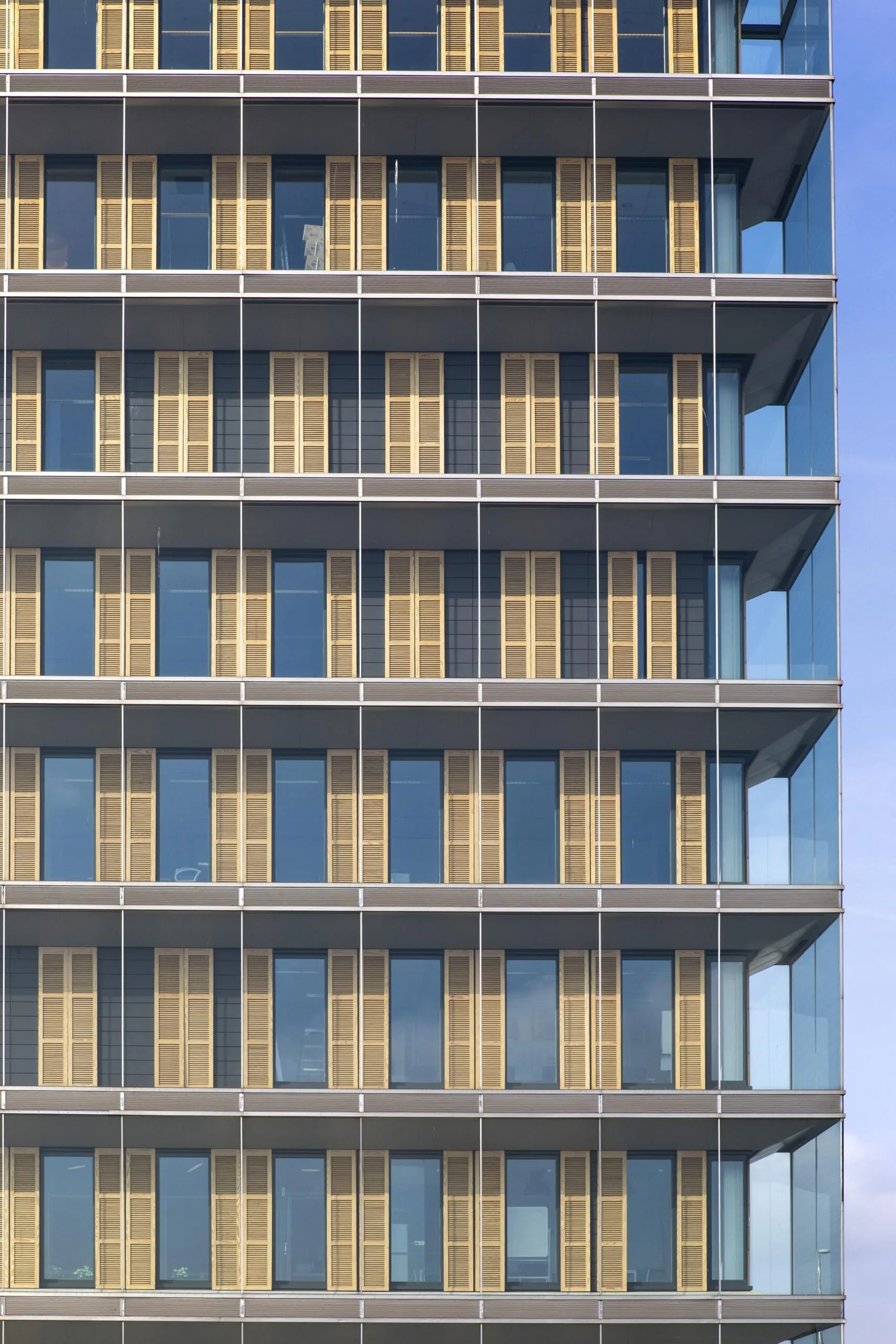 Gevel van het kantoorgebouw aan de Paasheuvelweg met glazen wanden en verticale houten lamellen.