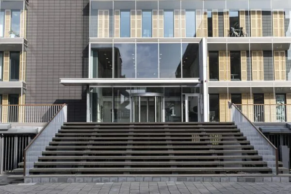 Entree van een modern kantoorgebouw aan de Paasheuvelweg met brede trappen en een glazen gevel.