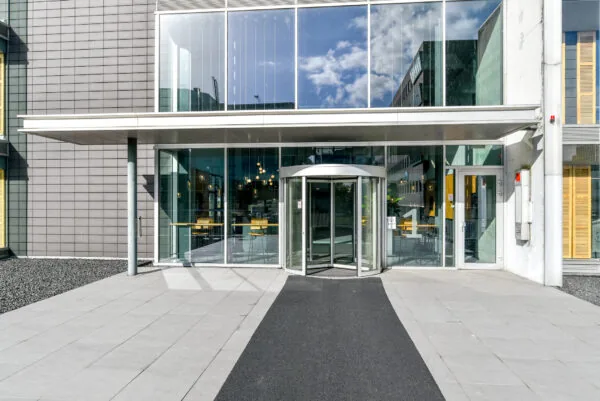 Hoofdingang van een modern kantoorgebouw aan de Paasheuvelweg met een glazen gevel en draaideur.