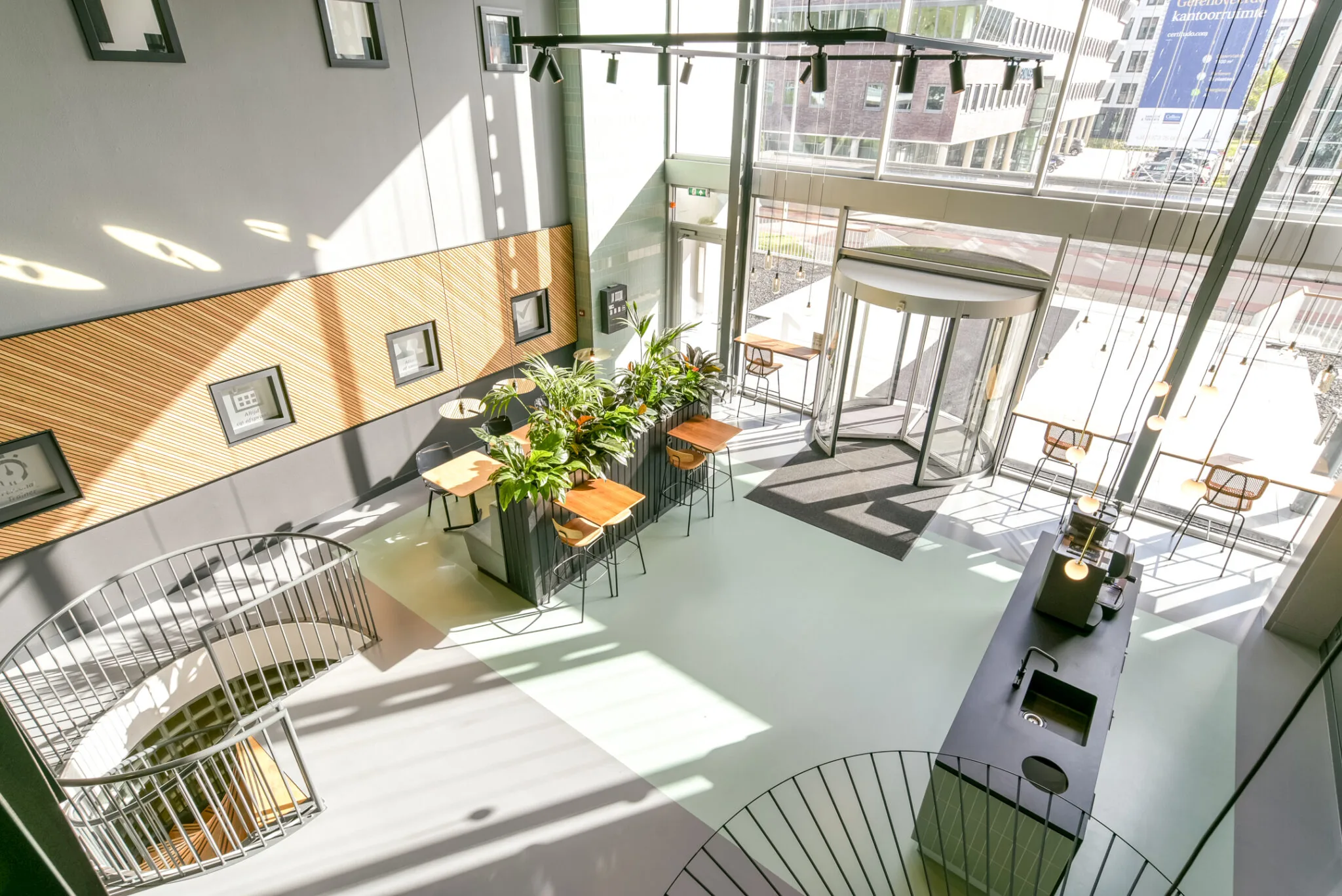 Moderne en lichte kantoorlobby aan de Paasheuvelweg met zithoeken, planten en een glazen draaideur.
