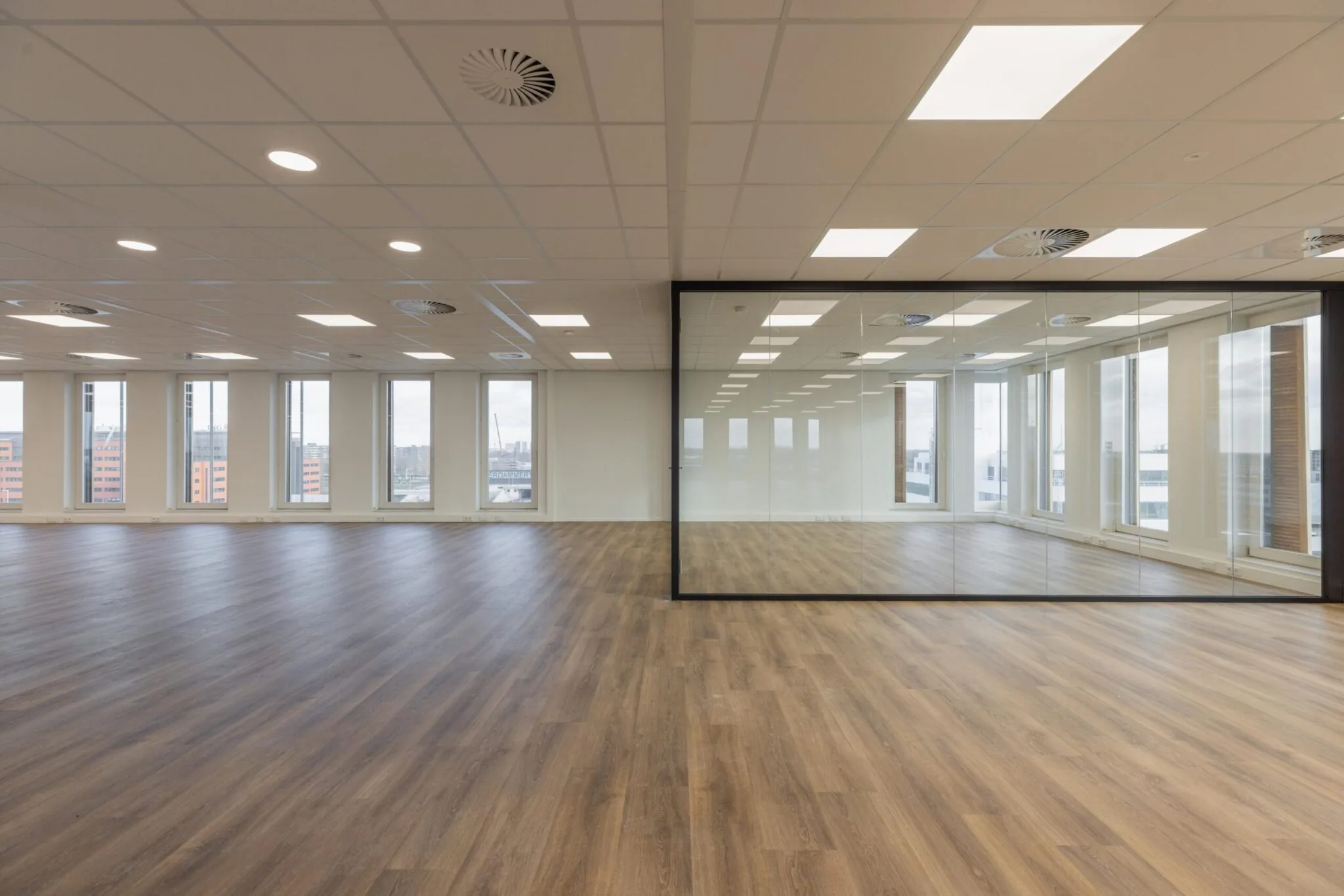 Licht en ruim kantoorpand aan de Paasheuvelweg met houten vloer en glazen vergaderruimte.