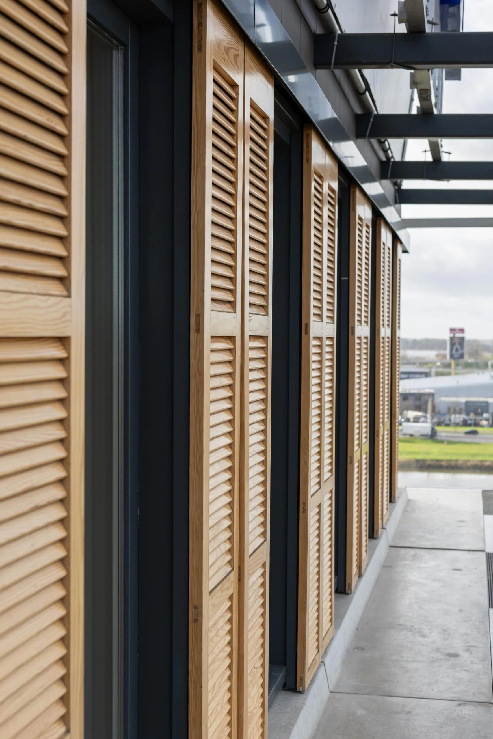 Houten lamellenluiken aan de gevel van een modern kantoorpand aan de Paasheuvelweg.