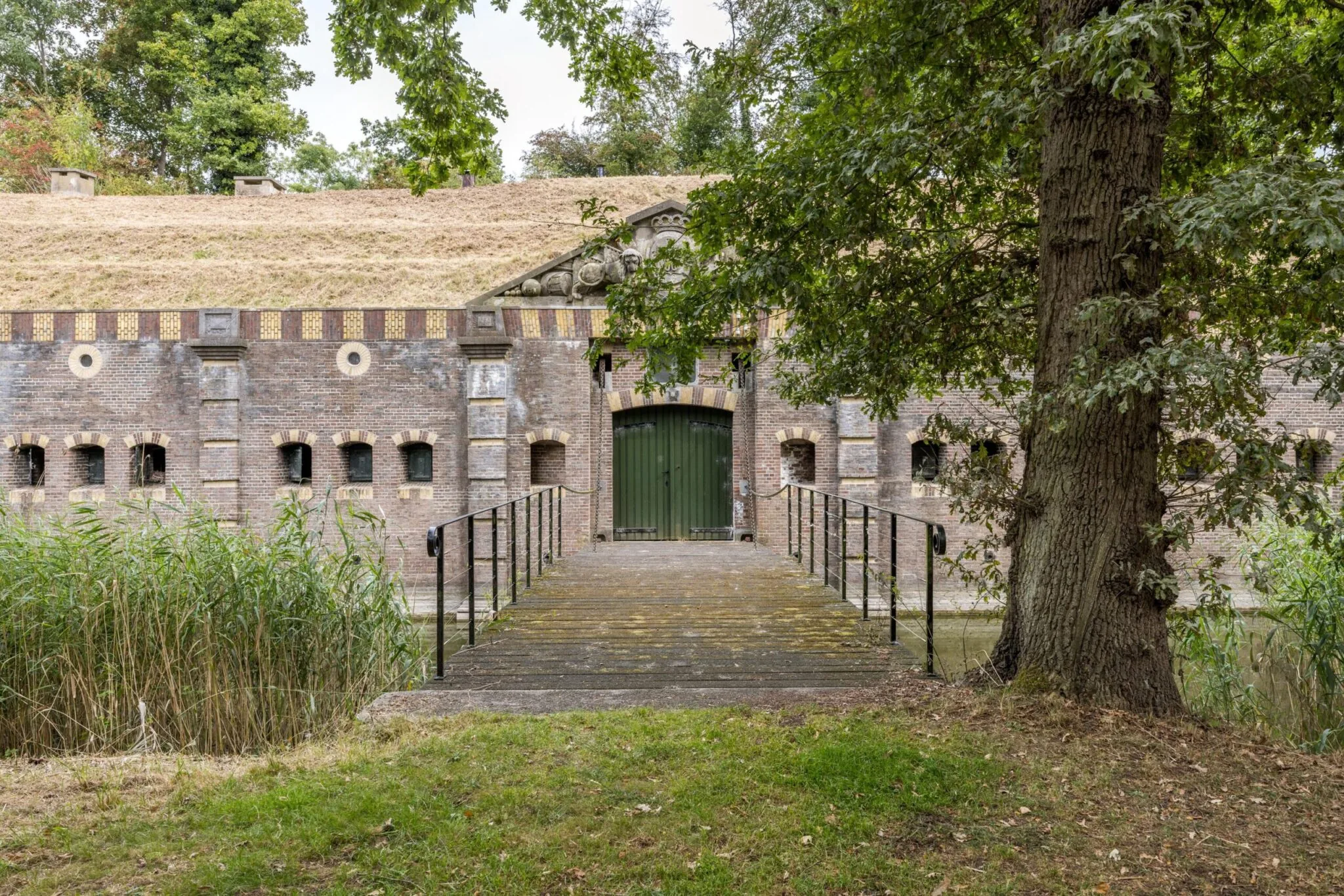 Ingang van Fort Vossegat met een ophaalbrug, omgeven door groen en water.