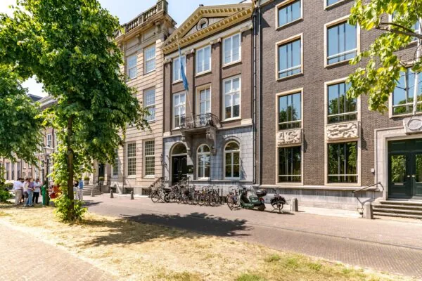 Straatbeeld van de Lange Vijverberg in Den Haag met historische gevels, fietsen en bomen op een zonnige dag.
