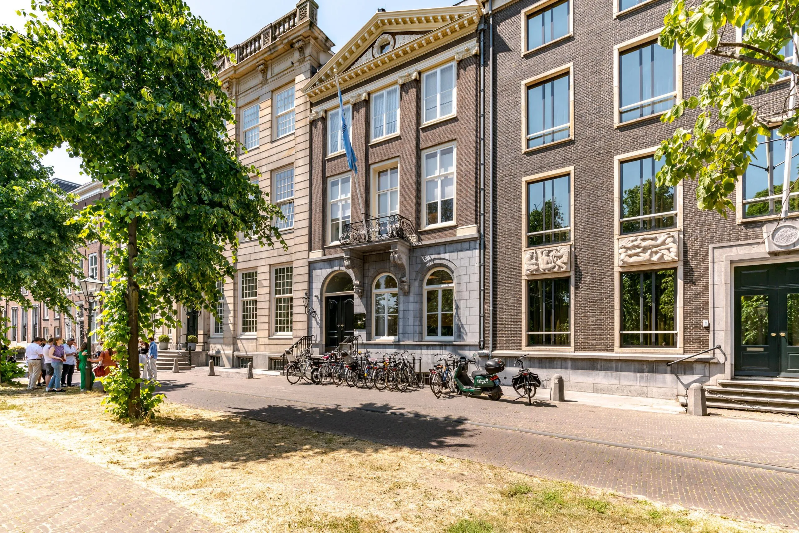 Straatbeeld van de Lange Vijverberg in Den Haag met historische gevels, fietsen en bomen op een zonnige dag.