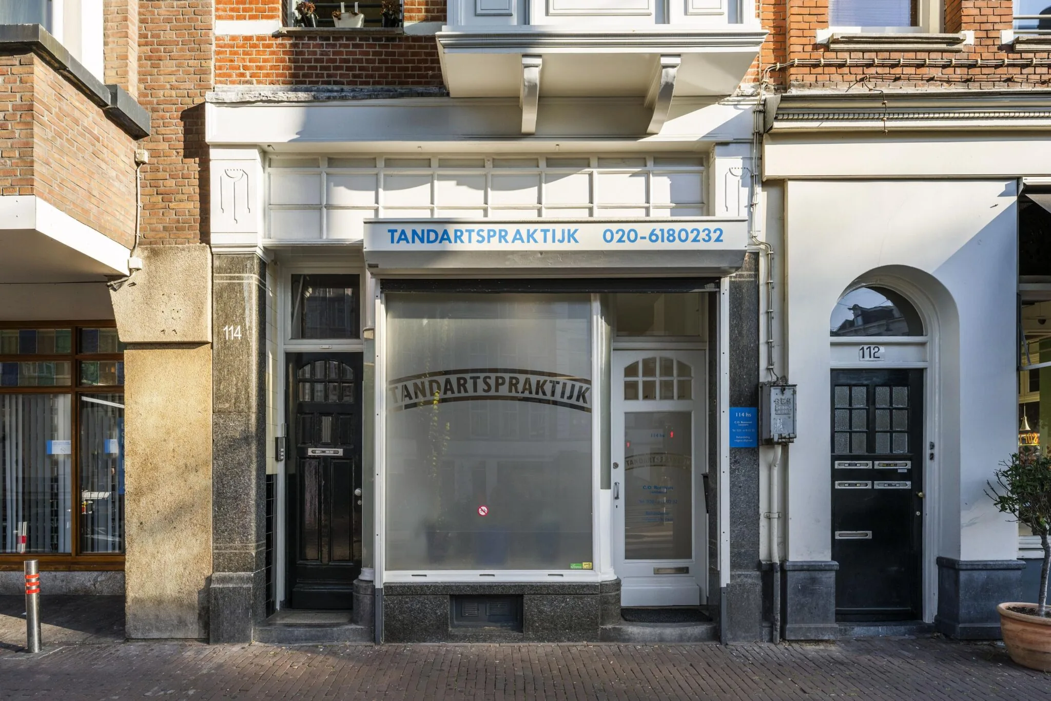 Voorgevel van een tandartspraktijk aan de Overtoom met huisnummer 114 in Amsterdam.